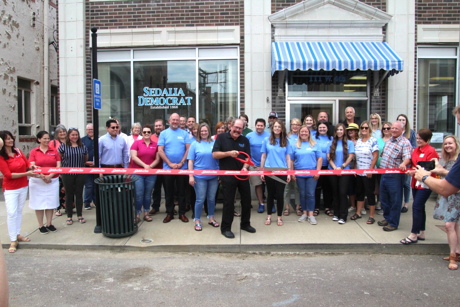 Surrounded by community members, elected officials and employees, Sedalia Democrat Publisher Jim Perry cuts the ribbon celebrating the Sedalia Democrat’s new location at 111 W. Fourth St. during an open house hosted Friday, June 10. The new building, formerly the Sedalia Water Department, is across the street from one of the Democrat’s past locations at 108-110 W. Fourth St.